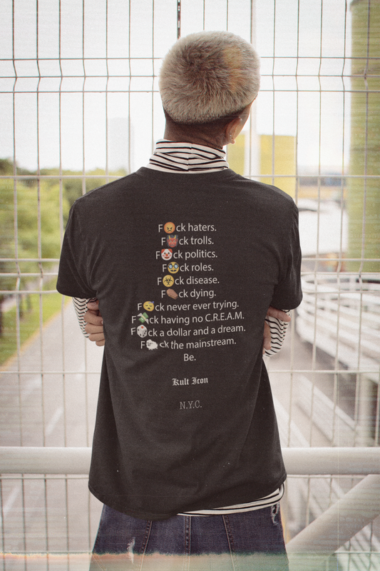 Person wearing a black t-shirt with text design, standing in front of a glass wall.