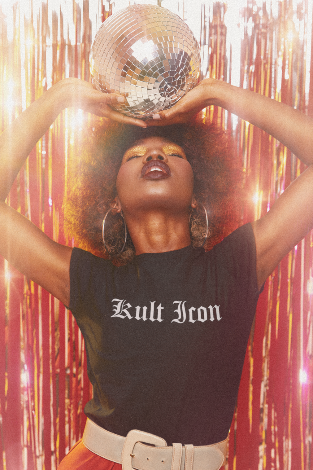 Person wearing a black 'Kult Iron' shirt with red pants against a festive background