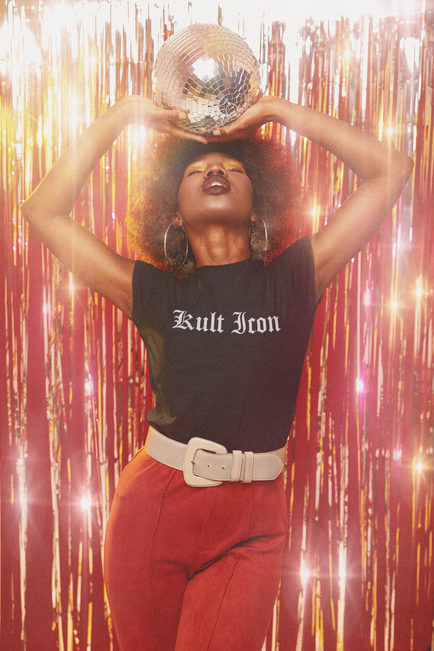 Person wearing a black 'Kult Iron' shirt with red pants against a festive background