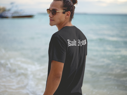Person wearing a black t-shirt with 'Built Iron' text by the ocean.