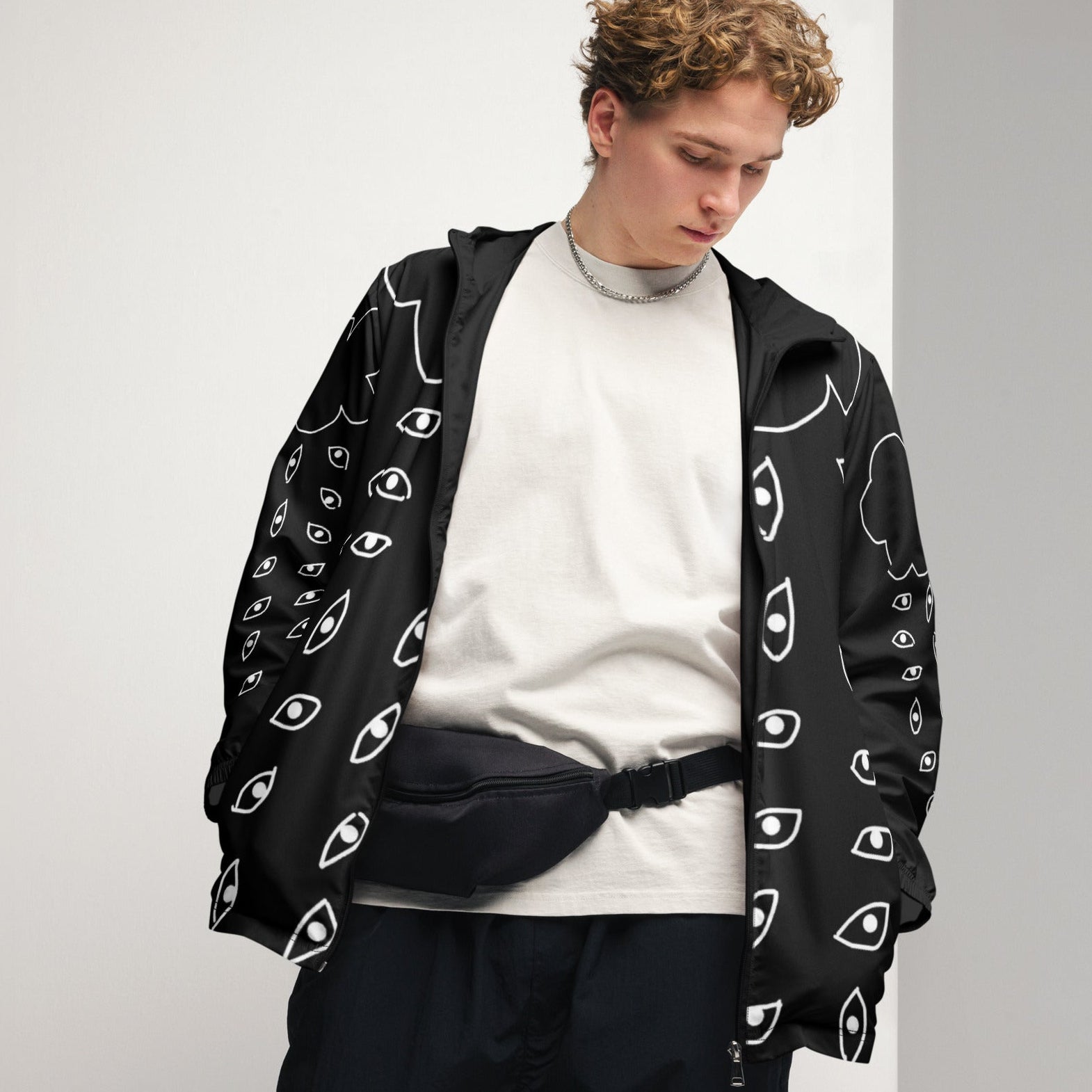 Person wearing a black hoodie with white eye pattern on a plain background