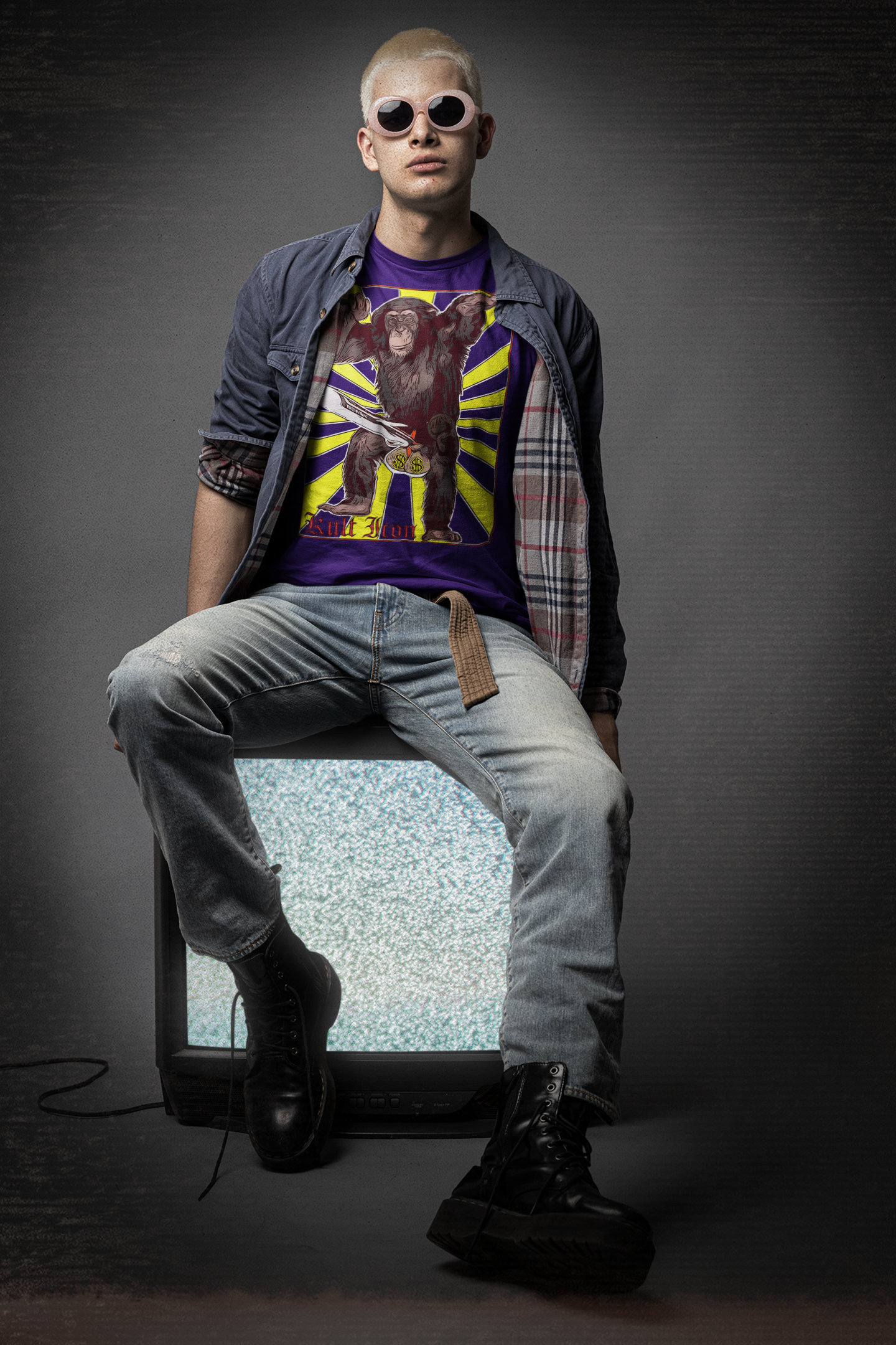 Person wearing a graphic t-shirt and sunglasses sitting on a vintage television set with a dark background