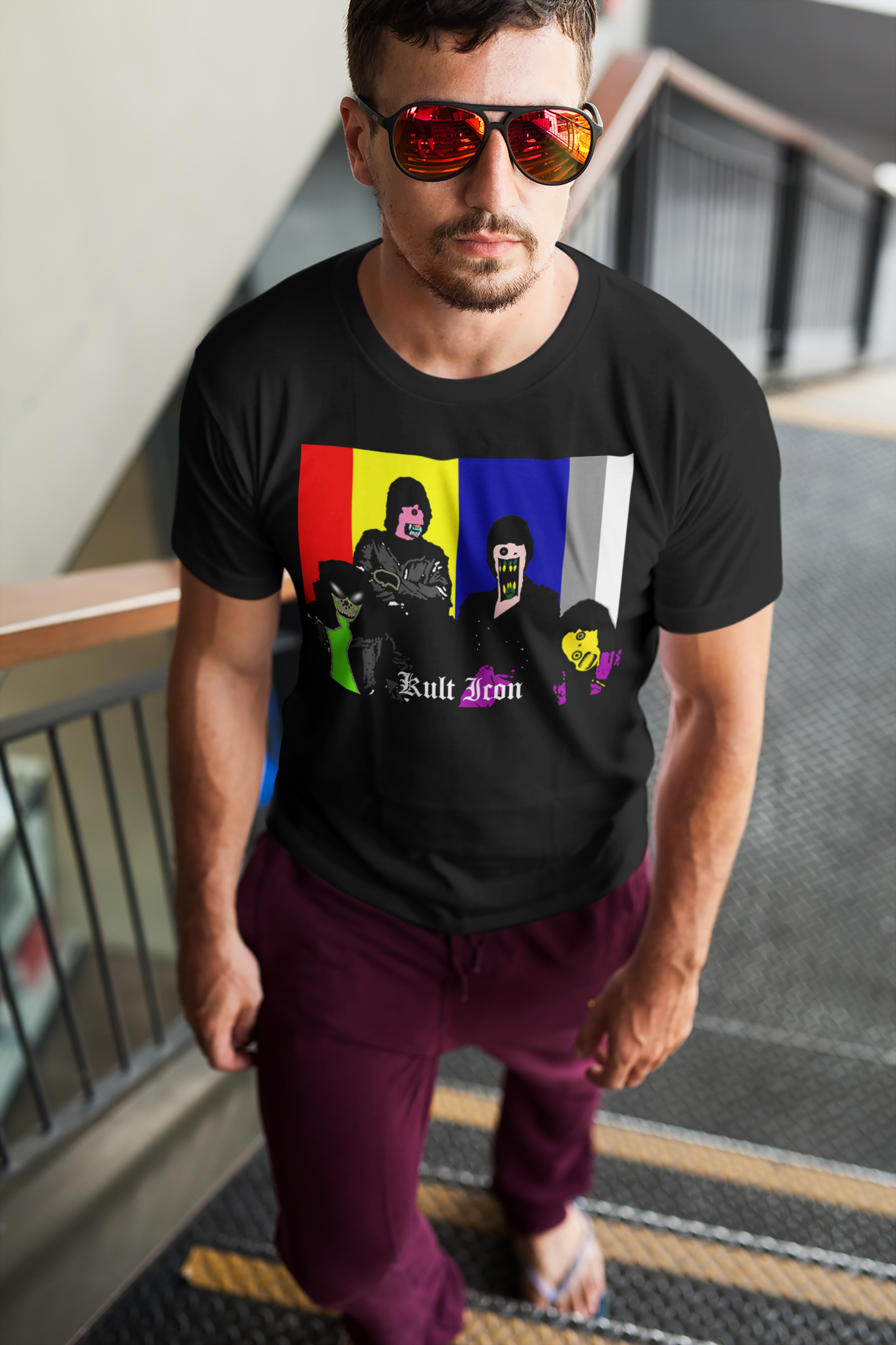 Man wearing a black t-shirt with colorful graphic design and sunglasses, standing on a staircase.