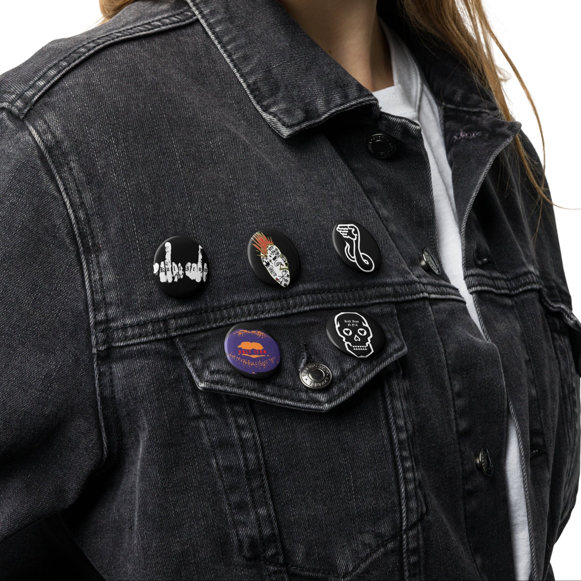 Black denim jacket with various pins on a white background