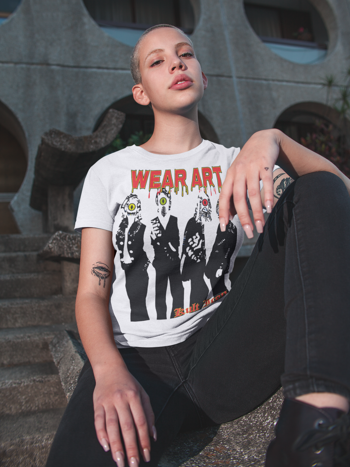 Person wearing a white t-shirt with graphic design sitting on steps.