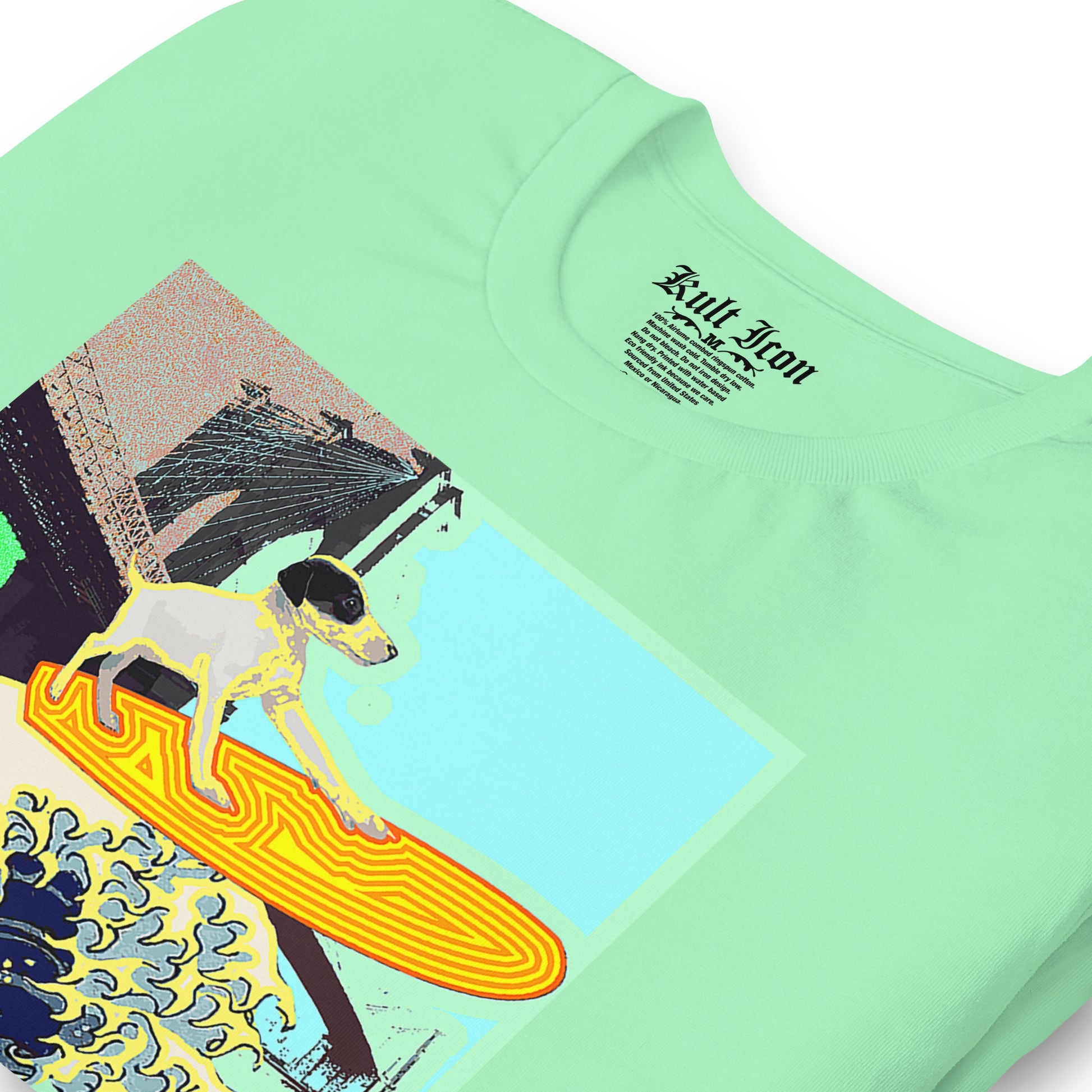 Light green t-shirt with a graphic of a dog on a surfboard and text on a white background