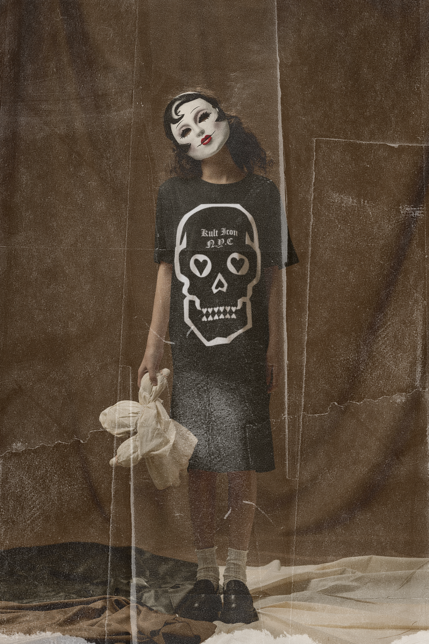 Person wearing a black t-shirt with a skull design and a white mask, standing against a textured brown background.